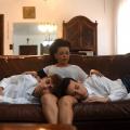 em cena de o primogenito, mãe está com 2 filhos no colo #paratodosverem 