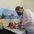 médica está examinando bebê sobre maca. #paratodosverem