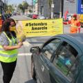 Mulher entrega panfleto a motorista e ao fundo faixa do setembro amarelo #paratodosverem