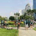 Pessoas de bicicleta ao redor de monumento na orla da praia #paratodosverem