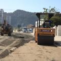 máquina compactadora percorre rua coberta de areia. #paratodosverem