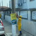 operário usando uniforme retira banner preso em poste. #paratodosverem