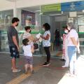 Casal e criança são recepcionados por profissionais na porta da unidade de saúde. #paratodosverem