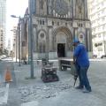 homem usa britadeira sobre piso diante de igreja. #paratodosverem