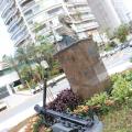 Âncora no jardim, em primeiro plano, e monumento do almirante Barroso e prédios ao fundo. #paratodosverem