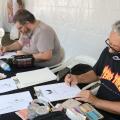 Quadrinistas desenham em papel sobre as mesas. #paratodosverem