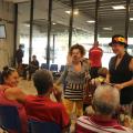 artistas vestidas de palhaça conversam com três pessoas que estão sentadas. Uma mulher ri. #paratodosverem