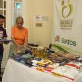 representante do evento e presidente do fundo social estão ao lado de mesa cheia de mantimentos. #paratodosverem