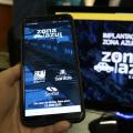 mão segurando celular com aplicativo zona azul aparecendo e tela com computador ao fundo #paratodosverem