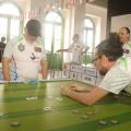 dois homens jogam botão em salão. #paratodosverem