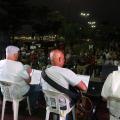 artistas tocando em palco e publico acompanhando sentado em praça #paratodosverem