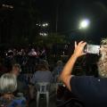 Mulher fotografa grupo em apresentação. #paratodosverem