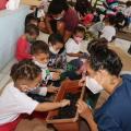 crianças com monitora colocam a mão em vaso com terra #paratodosverem