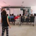 pessoas sentadas em frente a tenda aguardando atendimento cercadas pro gradis #paratodosverem