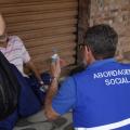 agente usando colete onde se lê nas costas abordagem social, conversa com homem que está sentado no chão de uma rua. #paratodosverem