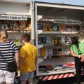pessoas olham livros em biblioteca móvel na rua #paratodosverem
