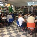 pessoas sentadas em mesas jogam rpg em biblioteca #paratodosverem