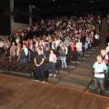 Palestrante no palco do Teatro do Sesc com plateia repleta de educadores. #paratodosverem