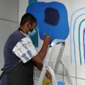 Homem faz pintura em parede da sala de ouvidoria na Subprefeitura dos Morros. #pracegover