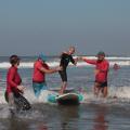 Jovem com deficiência pratica surfe adaptado com ajuda de instrutores. #paratodosverem