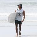 surfista segurando a prancha na praia #paratodosverem