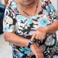 Senhora com pulseira do programa demonstra como acionar a teleassistência. #pratodosverem