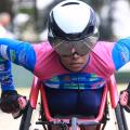 Paratleta, de óculos e capacete, corre em cadeira de rodas. #paratodosverem