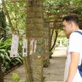 homem lê poesia em varal na entrada do orquidário. #paratodosverem