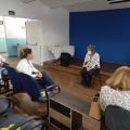 Auditório escolas com quatro pessoas conversando. Elas estão mantendo distanciamento umas das outras. #paratodosverem