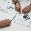 mãos sobre uma pesa apontam para folheto do cadoj. #paratodosverem