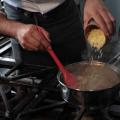 #fpracegover oto mostra homem adicionando tempero em panela com feijão sobre o fogão