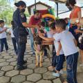 Crianças passam a mão em cachorro do canil da guarda com agente ao lado #paratodosverem