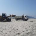 retroescavadeira leva areia para outro caminhão na praia #paratodosverem