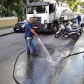 homem segura mangueira que joga água em rua #paratodosverem