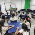 pai de aluno lê livro e crianças observam em sala de aula #paratodosverem