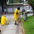 trabalhadores realizam serviços de raspação agachados no meio fio e ao lado de jardim #paratodosverem