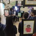 alunos em sala com várias obras em exposição penduradas #paratodosverem