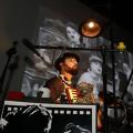 artista tocando no palco com filme sendo exibido ao fundo #paratodosverem