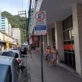 rua do centro com veículos estacionados à direita e placa referente à zona azul. #paratodosverem