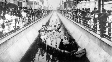 imagem de 1907 de inauguração de canal, com pessoas em embarcações dentro do canal, e fora, assistindo. #paratodosverem 