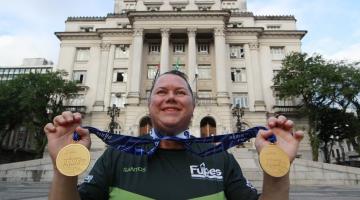 Beth gomes mostra medalhas na frente da prefeitura #paratodosverem