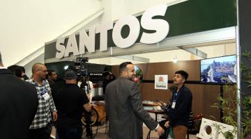 Estande com o letreiro escrito Santos em destaque é visitado por gestores e investidores. #pratodosverem