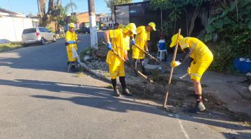 homens uniformizados removem mato de sarjeta. #paratodosverem 