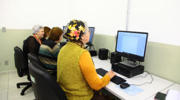 Mulheres idosas estão sentadas diante de desktops. #Paratodosverem