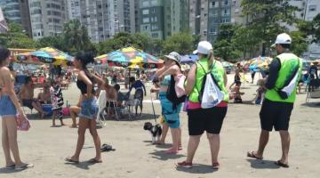 agentes uniformizados abordam mulher que está com cachorro na faixa de areia. #paratodosverem