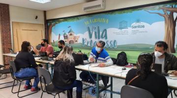 Pessoas sentadas sendo atendidas por funcionários. #paratodosverem