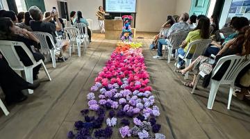 artesãos assistem a palestra com flores decorando o meio do salão #paratodosverem