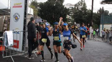 três atletas correndo de mãos dadas cruzando a chegada #paratodosverem