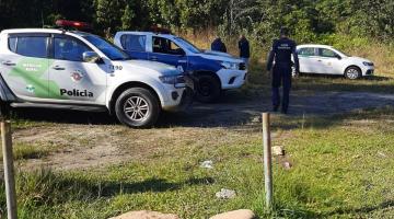 Em primeiro plano areia e ao fundo viaturas estacionadas. #paratodosverem