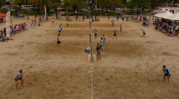 Várias pessoas em competição de futevolei na areia da praia #paratodosverem